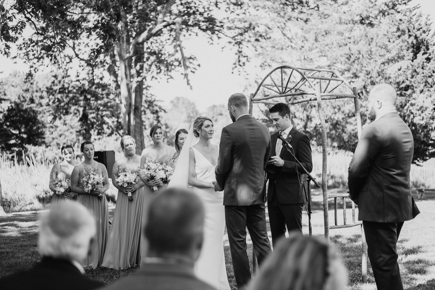 Black and white photo showing wedding guests seated for an outdoor ceremony.