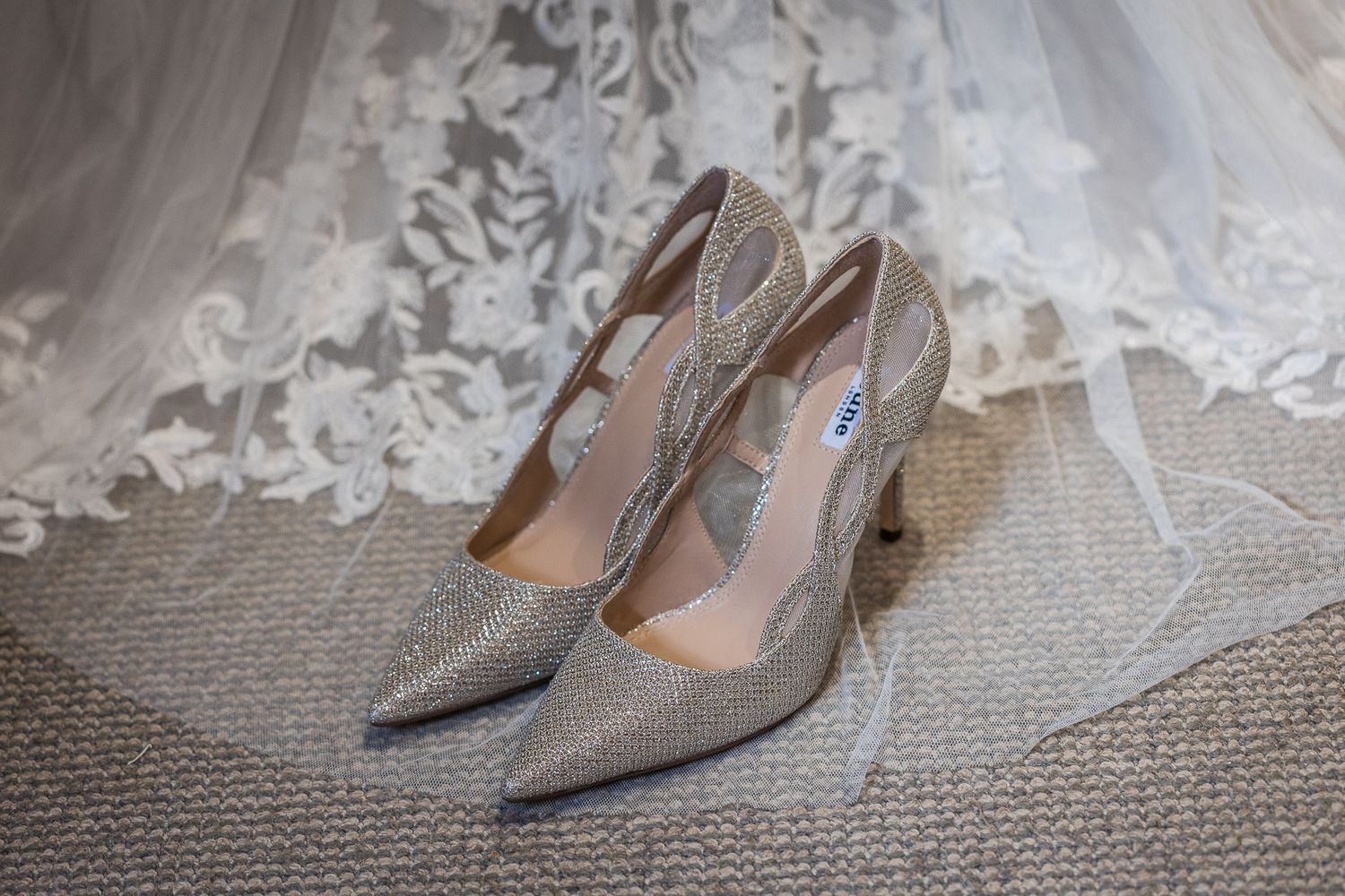 Sparkly silver wedding heels positioned next to delicate lace veil.