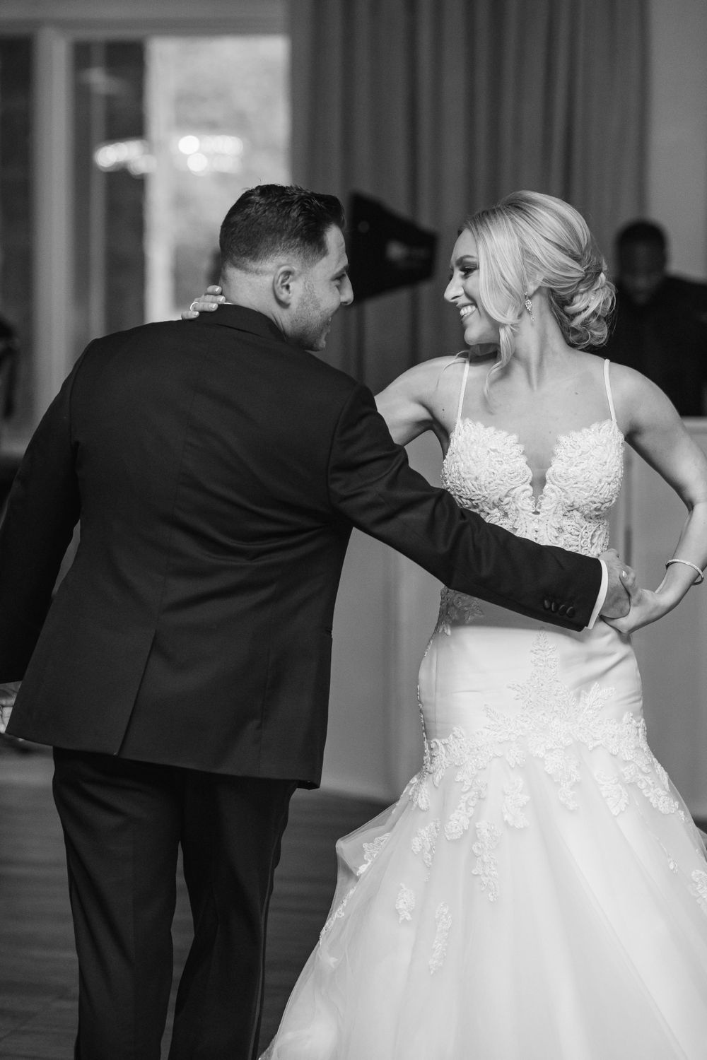 Dancing couple in formal wedding attire on ballroom floor.