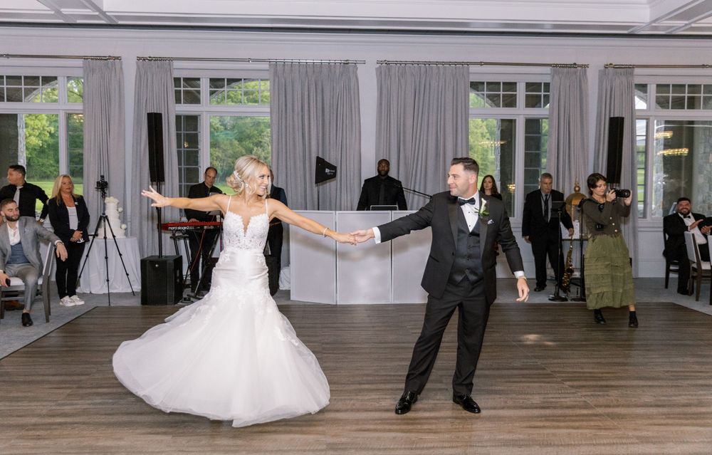 Newlyweds perform first dance in elegant reception space with guests looking on.