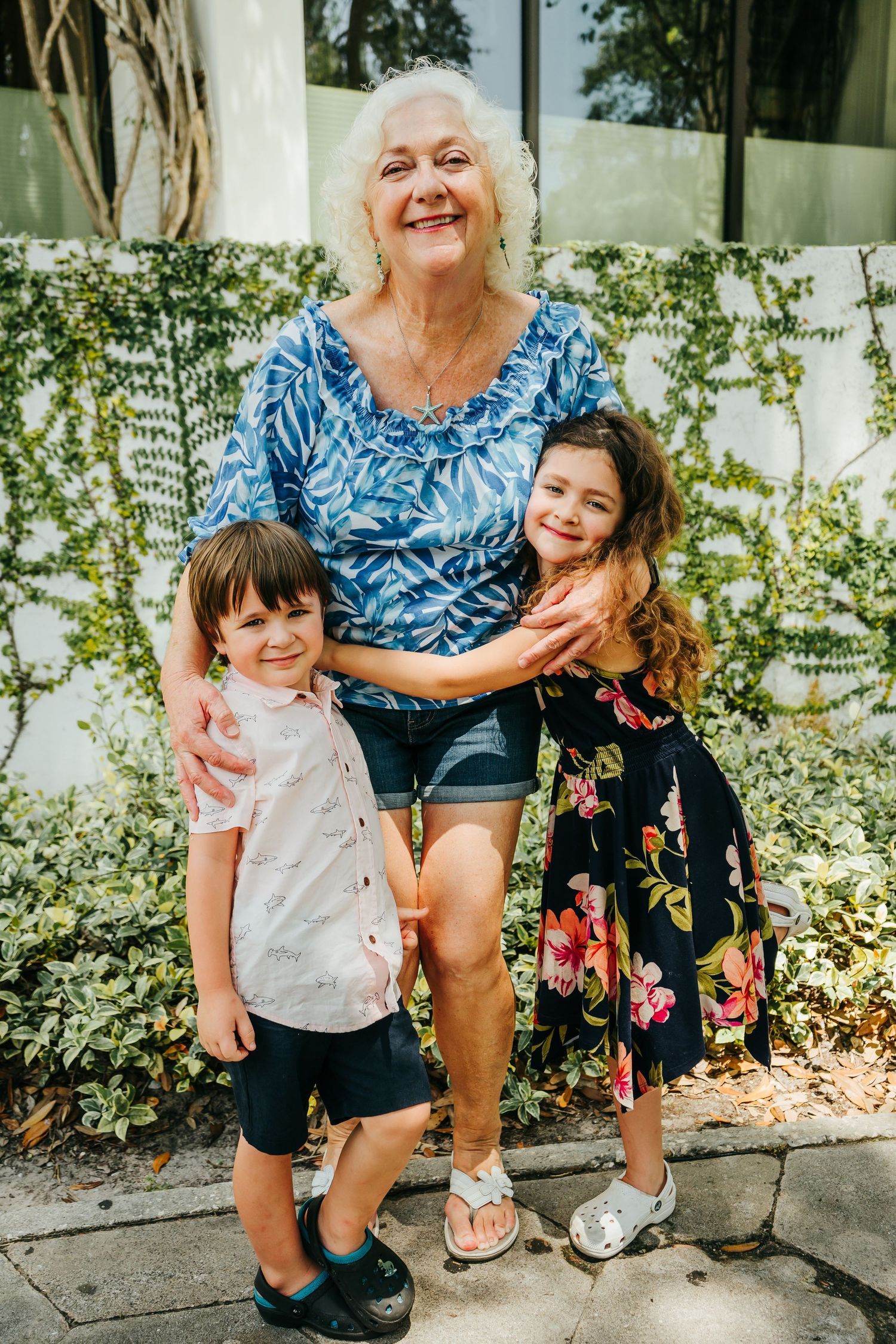 Outdoor Family Session in St. Pete, FL; Grandmother posing with grandkids near vine covered wall