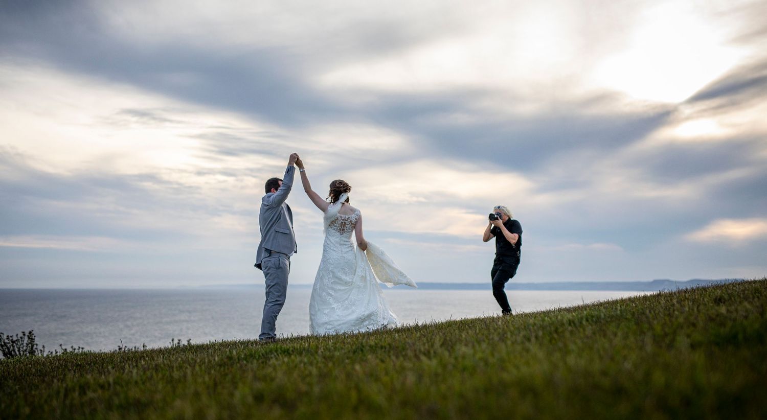 Silhouettes against sunset sky showing wedding photography poses on a hillside.