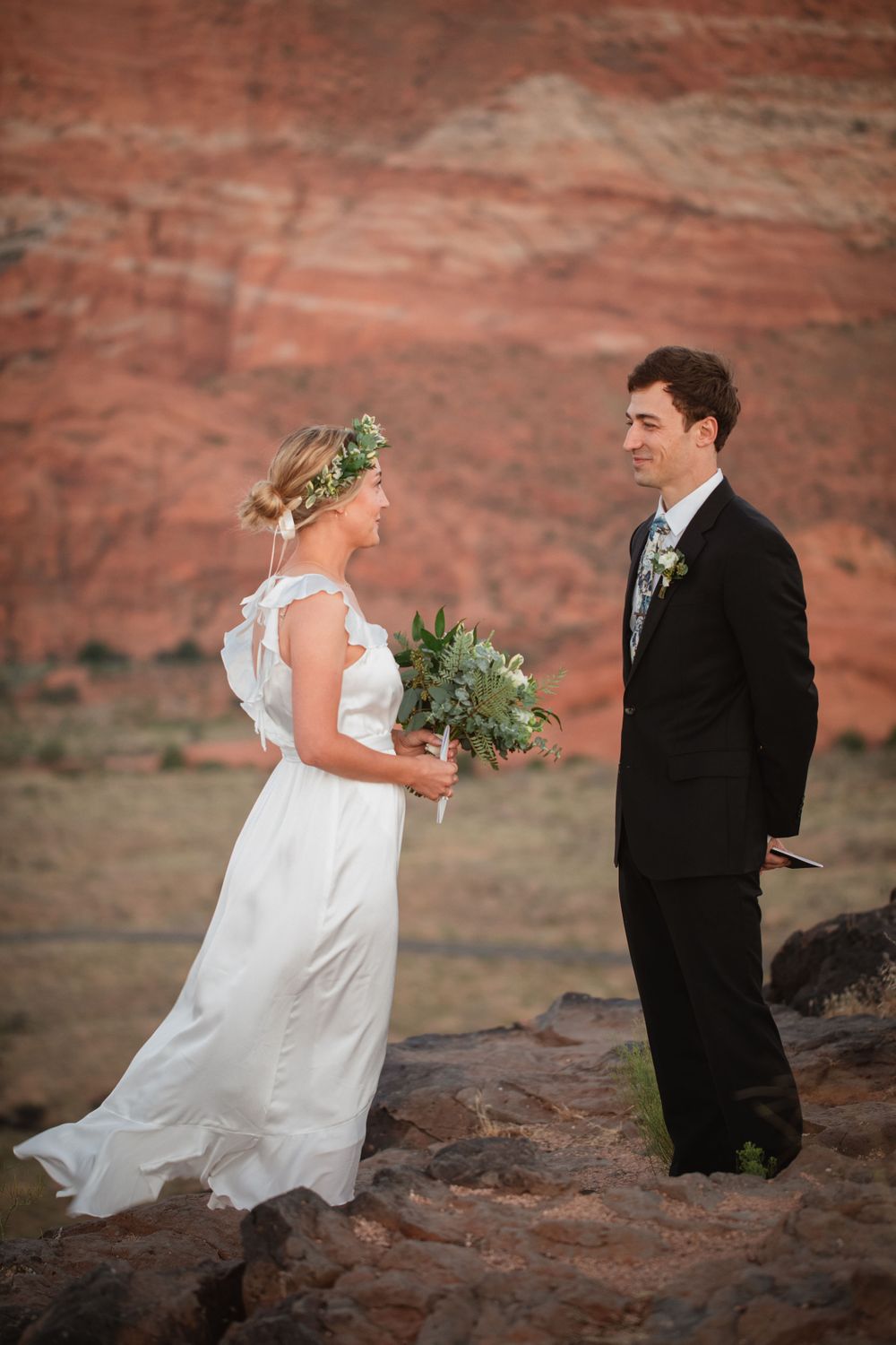 Bride and groom exchange vows at red rock canyon overlook during outdoor desert wedding ceremony.