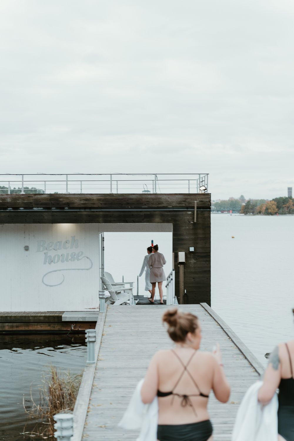 People in swimwear walking on dock near waterfront building.