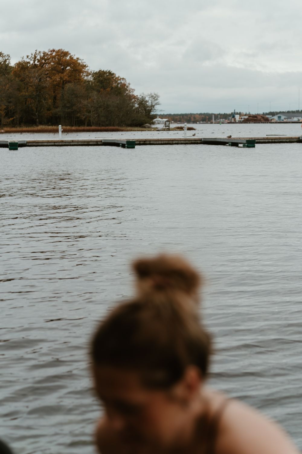 Scenic view of wooden dock and calm lake water on cloudy autumn day.