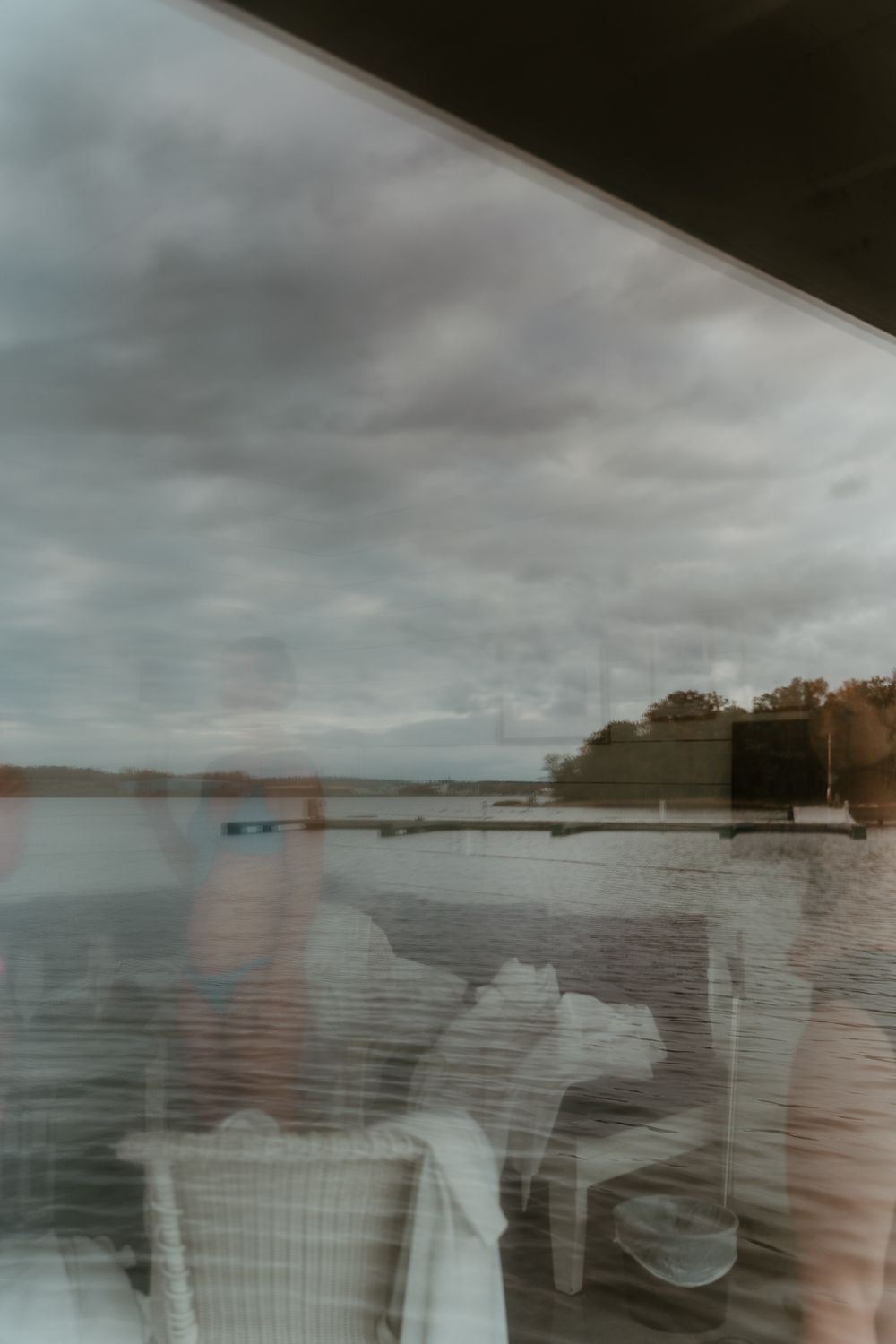 Moody lakeside landscape with dock and cloudy sky reflected in still waters.