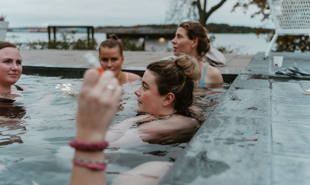 Several swimmers enjoy a warm soak in an outdoor pool on a cloudy day.