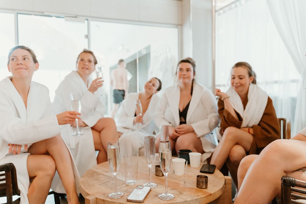 Group relaxing in white bathrobes with drinks at spa.