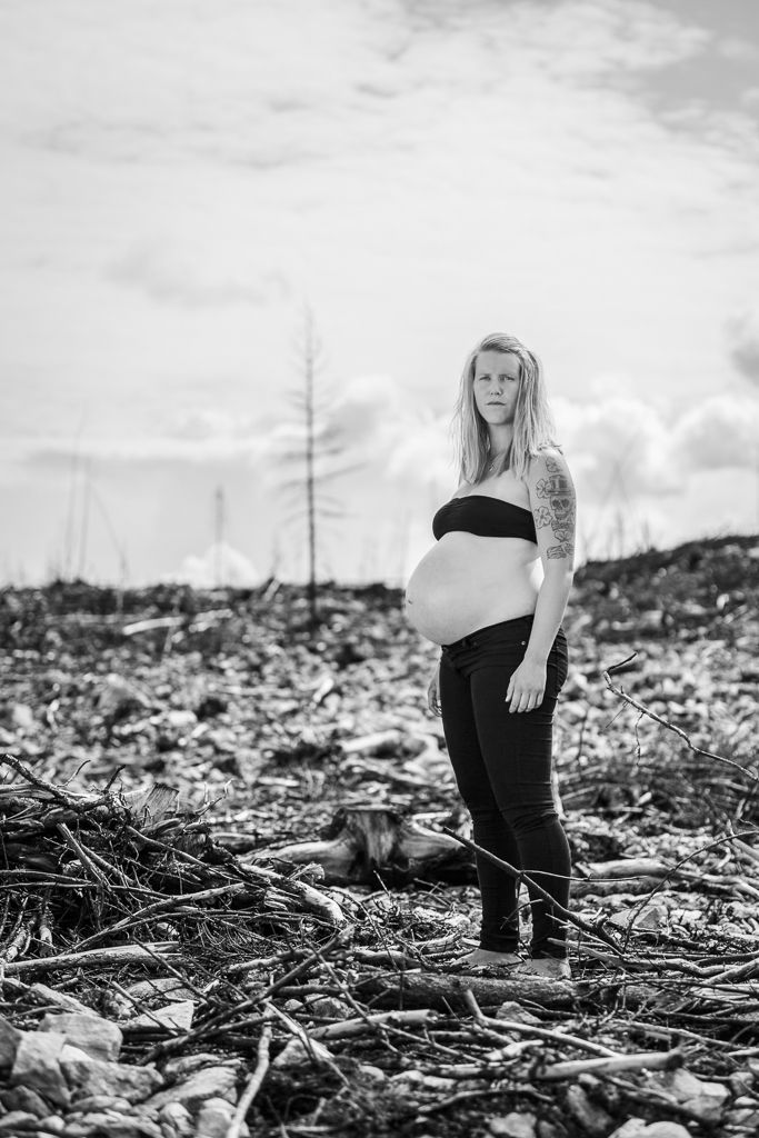 Gravid kvinna står kraftfullt i nedbrunnen sko. Gravidfotografering i Västmanland utanför Västerås.