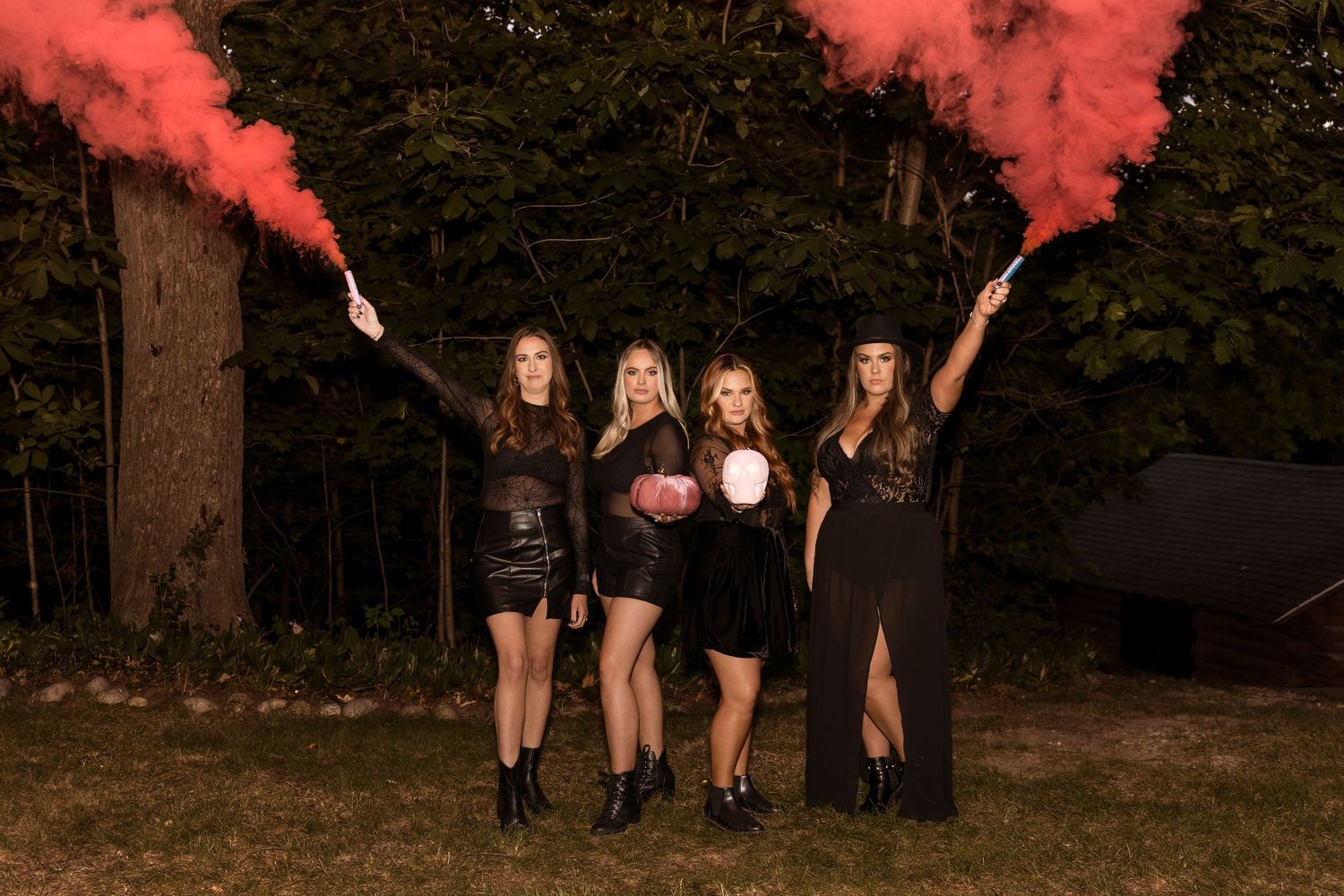 Group holds red smoke flares while posing outdoors in dark attire.