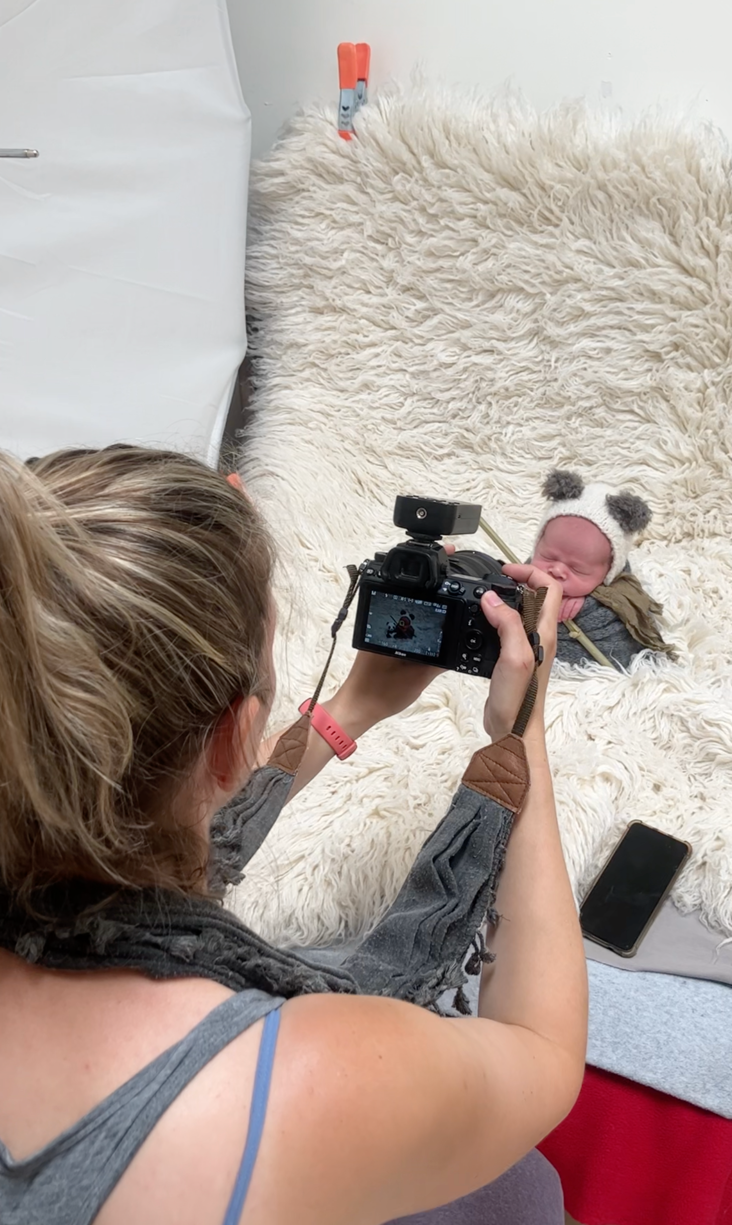 Behind-the-scenes photo of newborn photography session with professional camera setup.