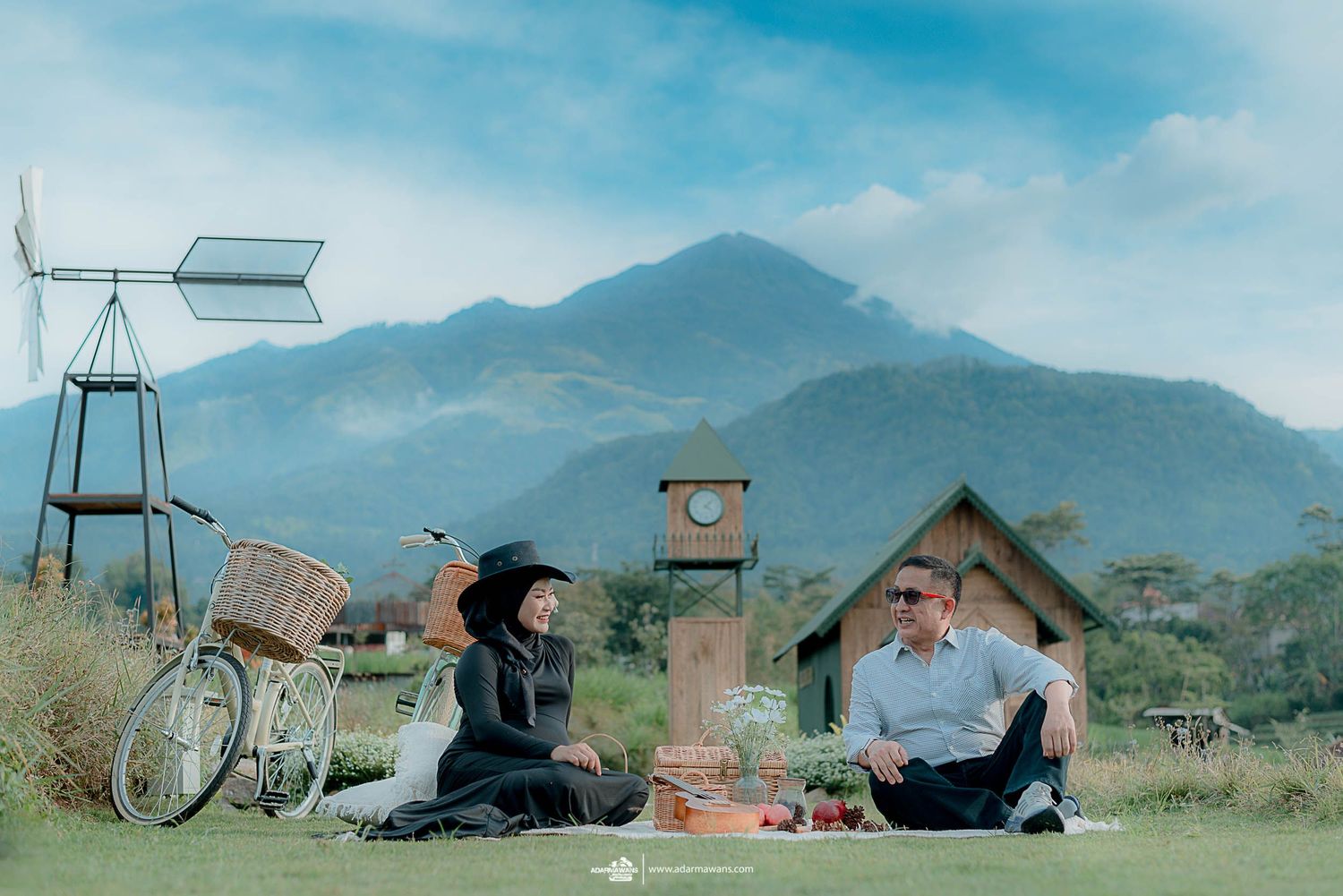 Couple enjoying outdoor picnic with vintage bicycle and mountain vista.