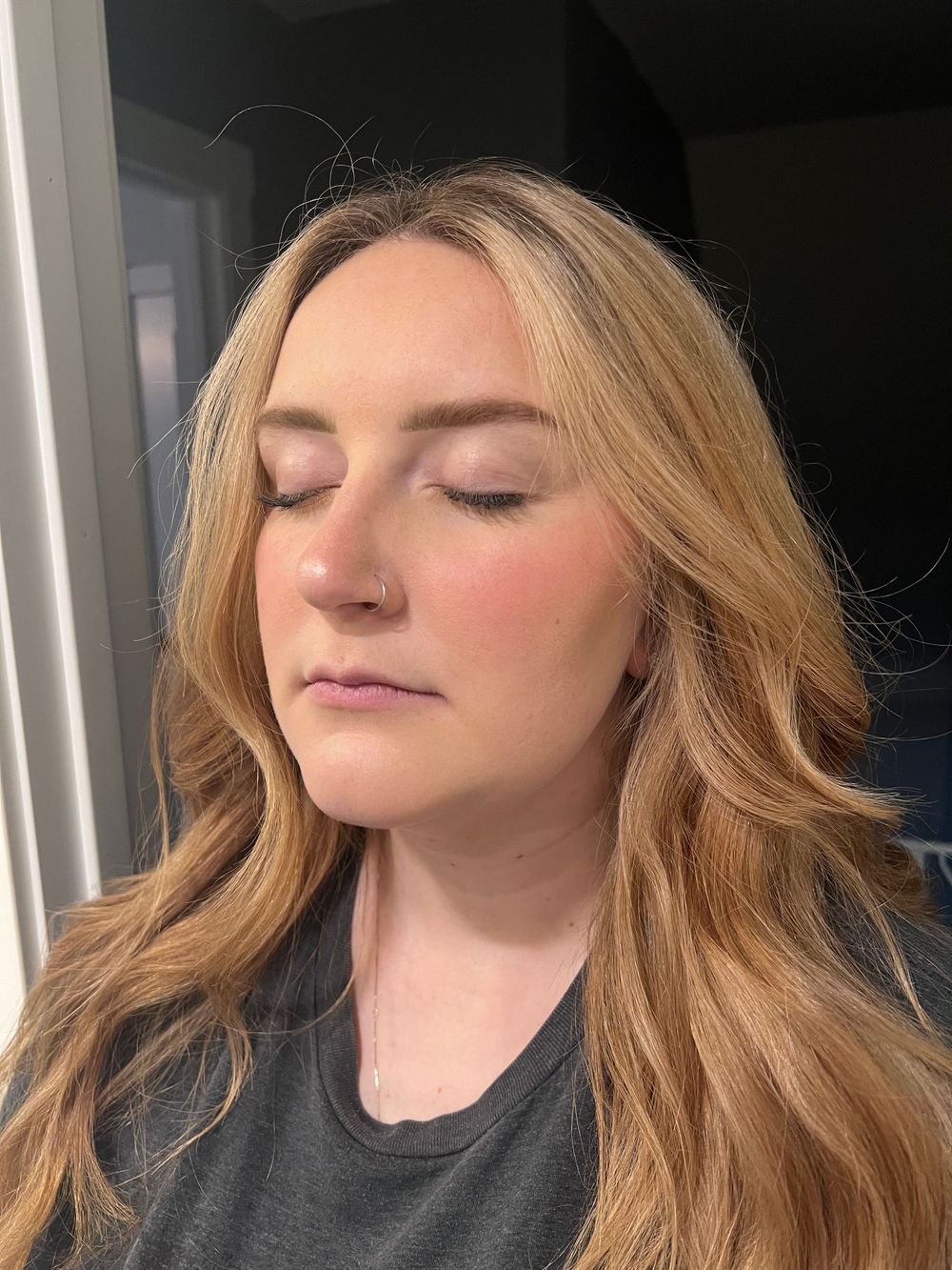 Close-up of wavy blonde hair with natural makeup in indoor lighting.