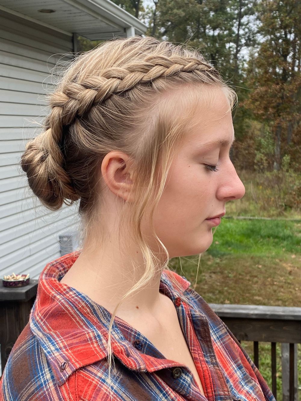 Side profile showing an elegant braided updo hairstyle with a red plaid shirt.