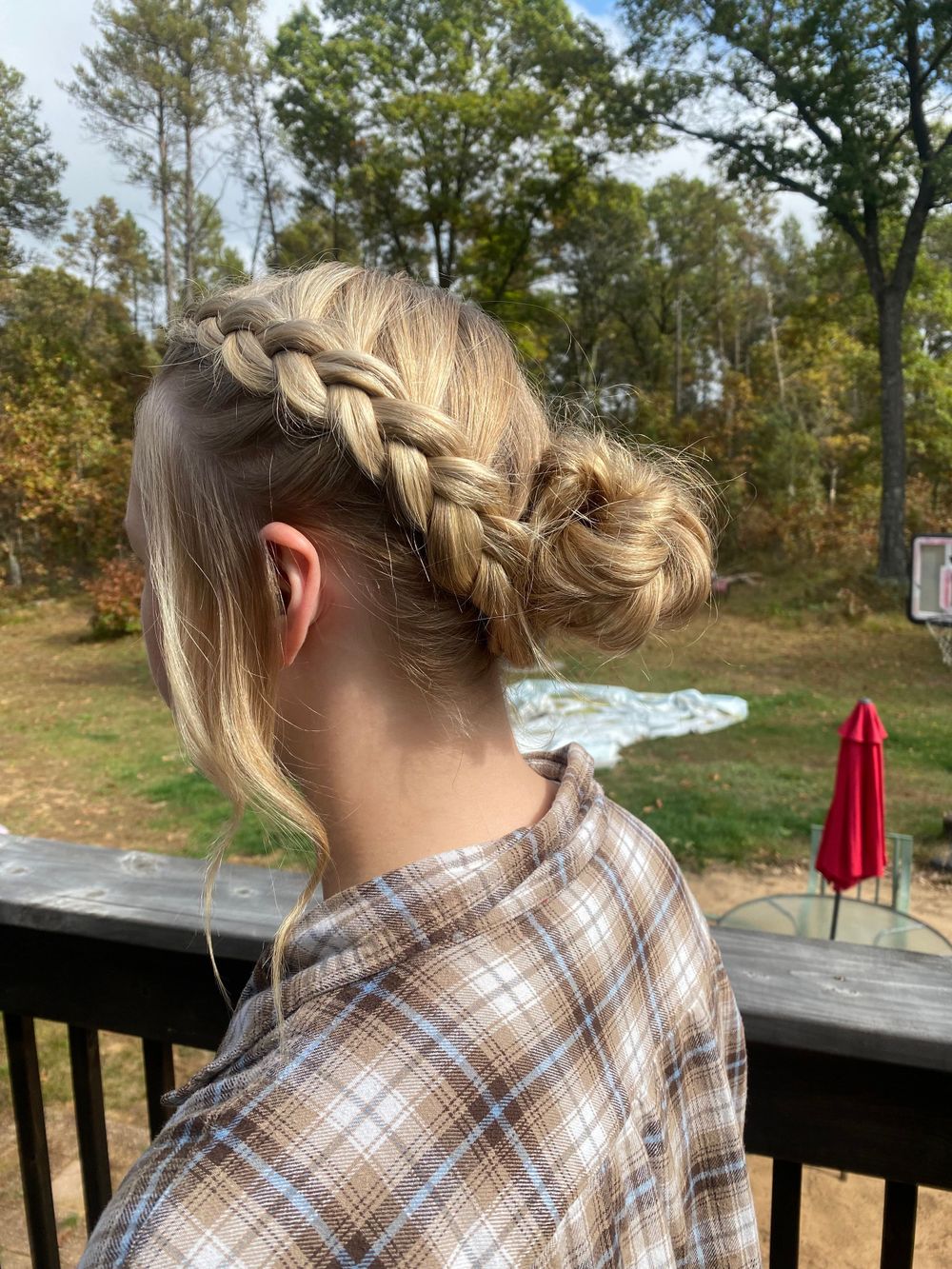 Detailed view of a braided hairstyle with blonde hair against an autumn outdoor setting.