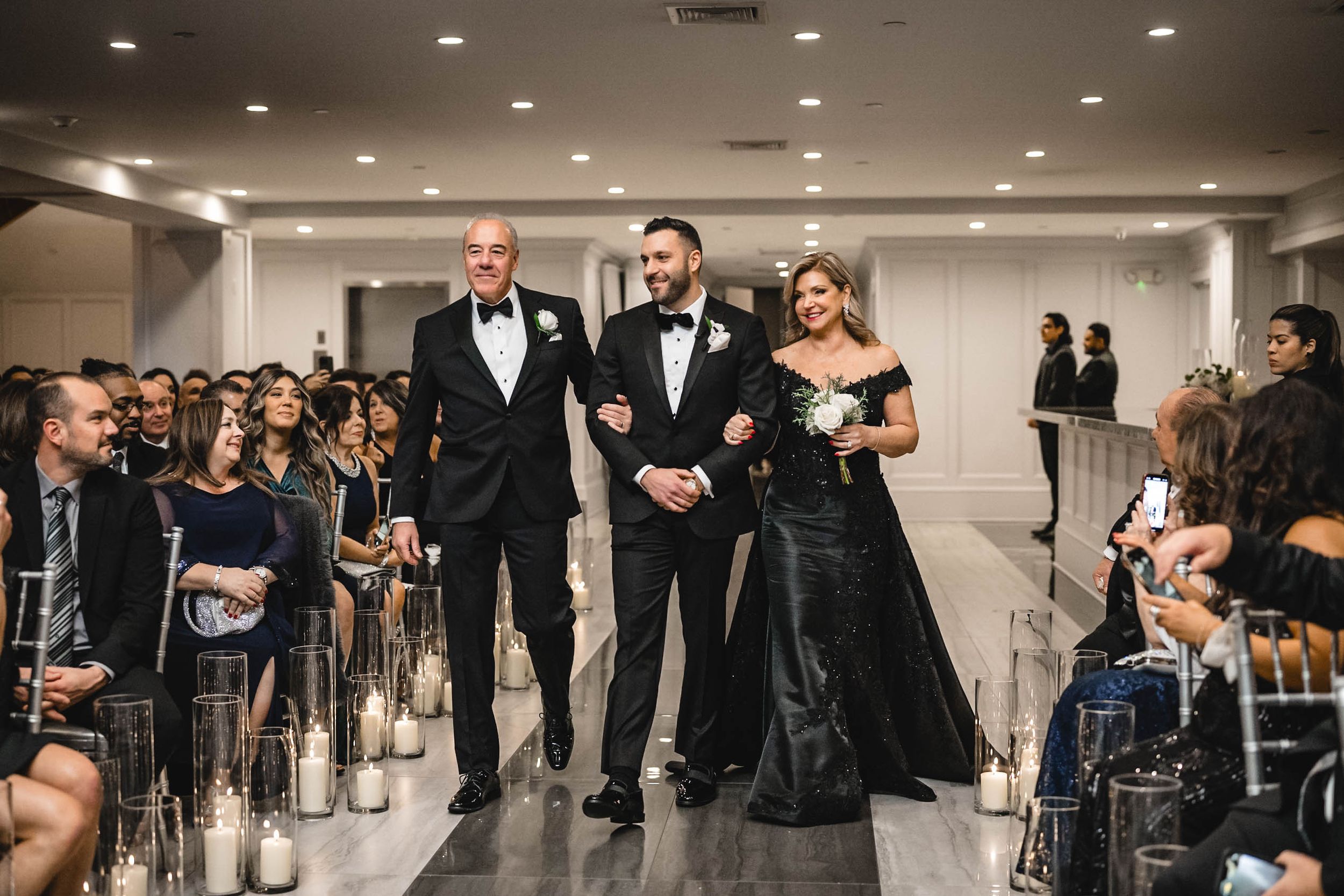 Wedding reception venue with guests seated at round tables and elegant white decor.