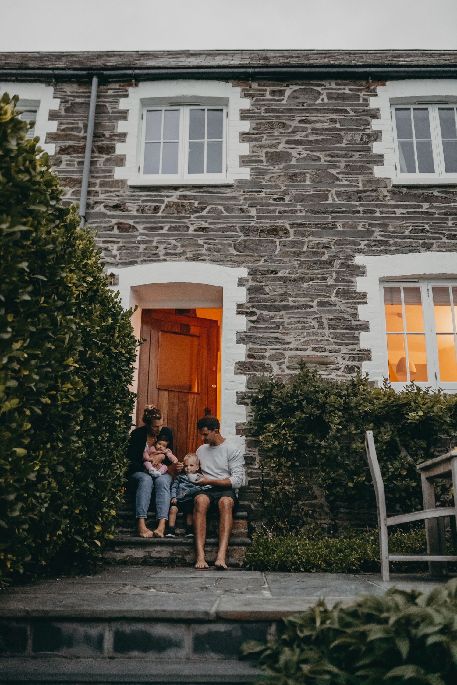 Couple relaxing on stone steps of rustic cottage with traditional architecture.