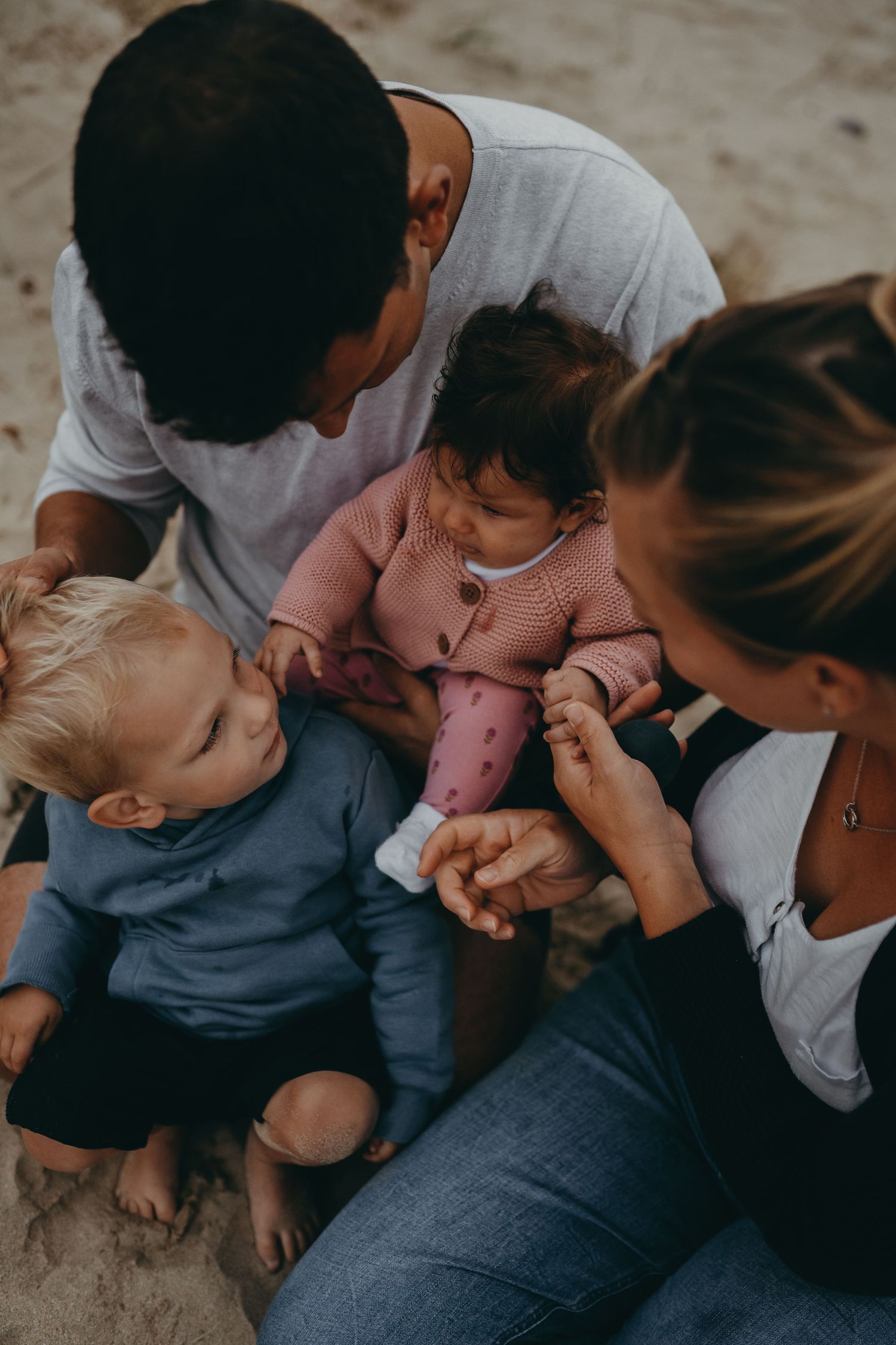 An intimate family moment shared while sitting together on the beach.