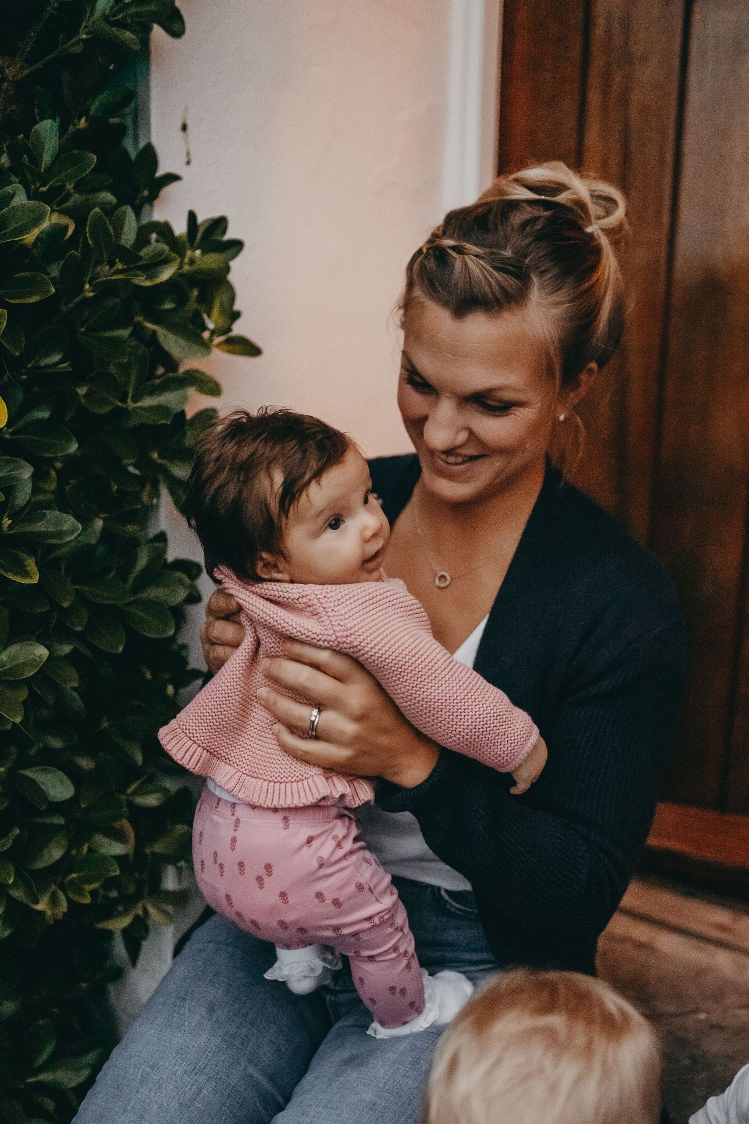 Sweet moment between parent and child in pink sweater on doorstep.