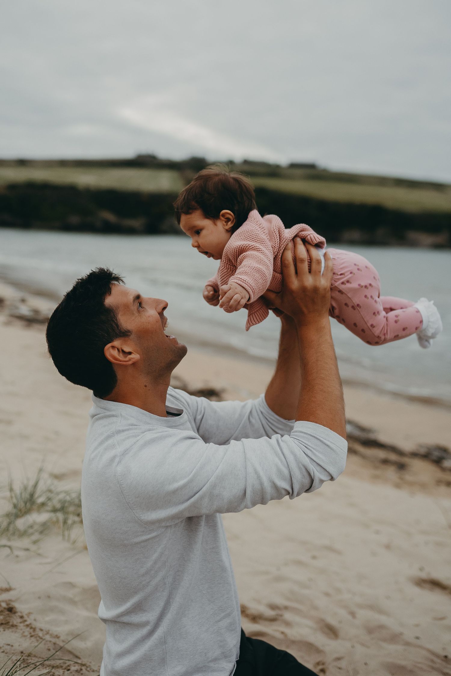 A tender moment captured between a parent and baby playing on a sandy beach.