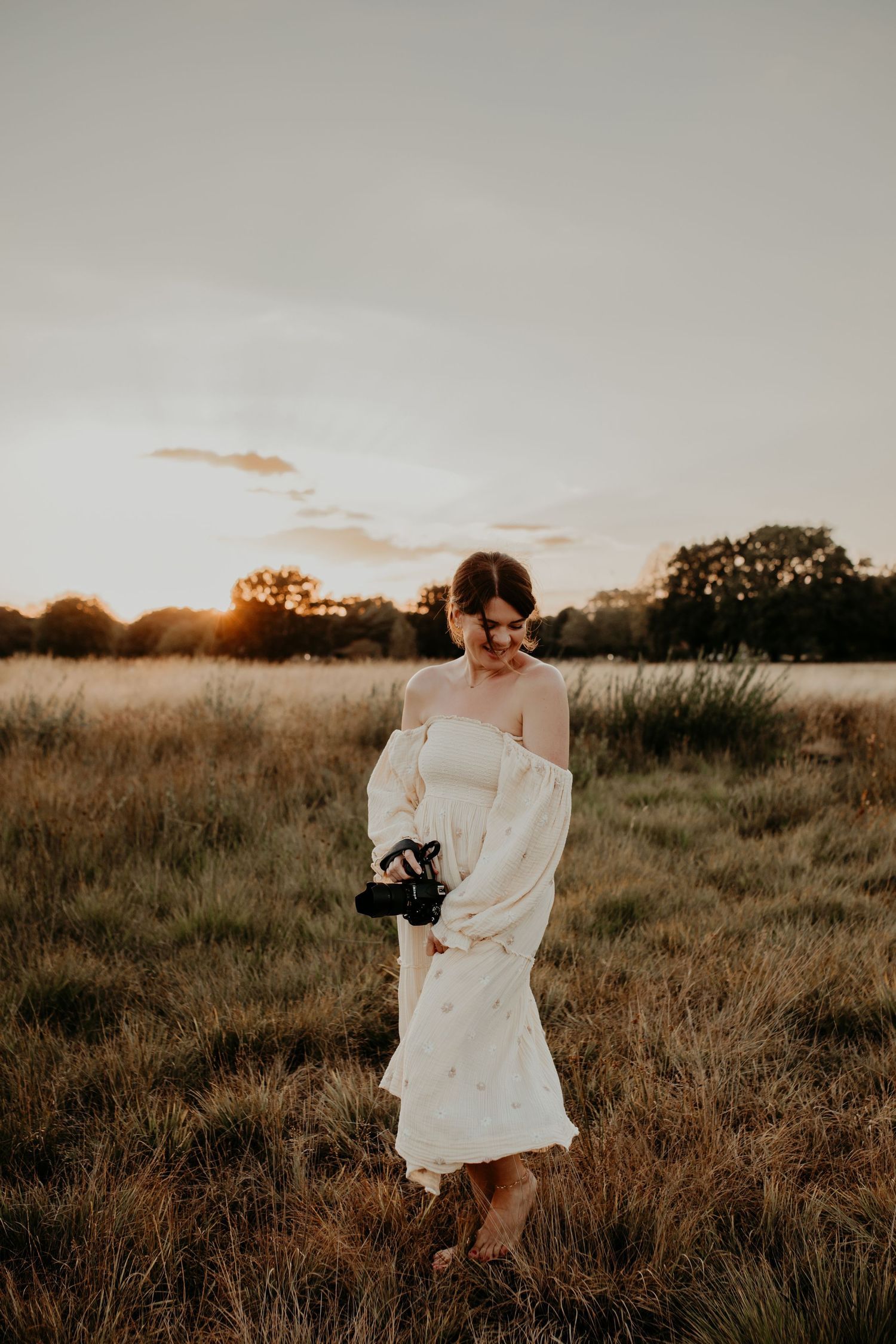 A flowing white dress catches the golden light during sunset in a grassy field.