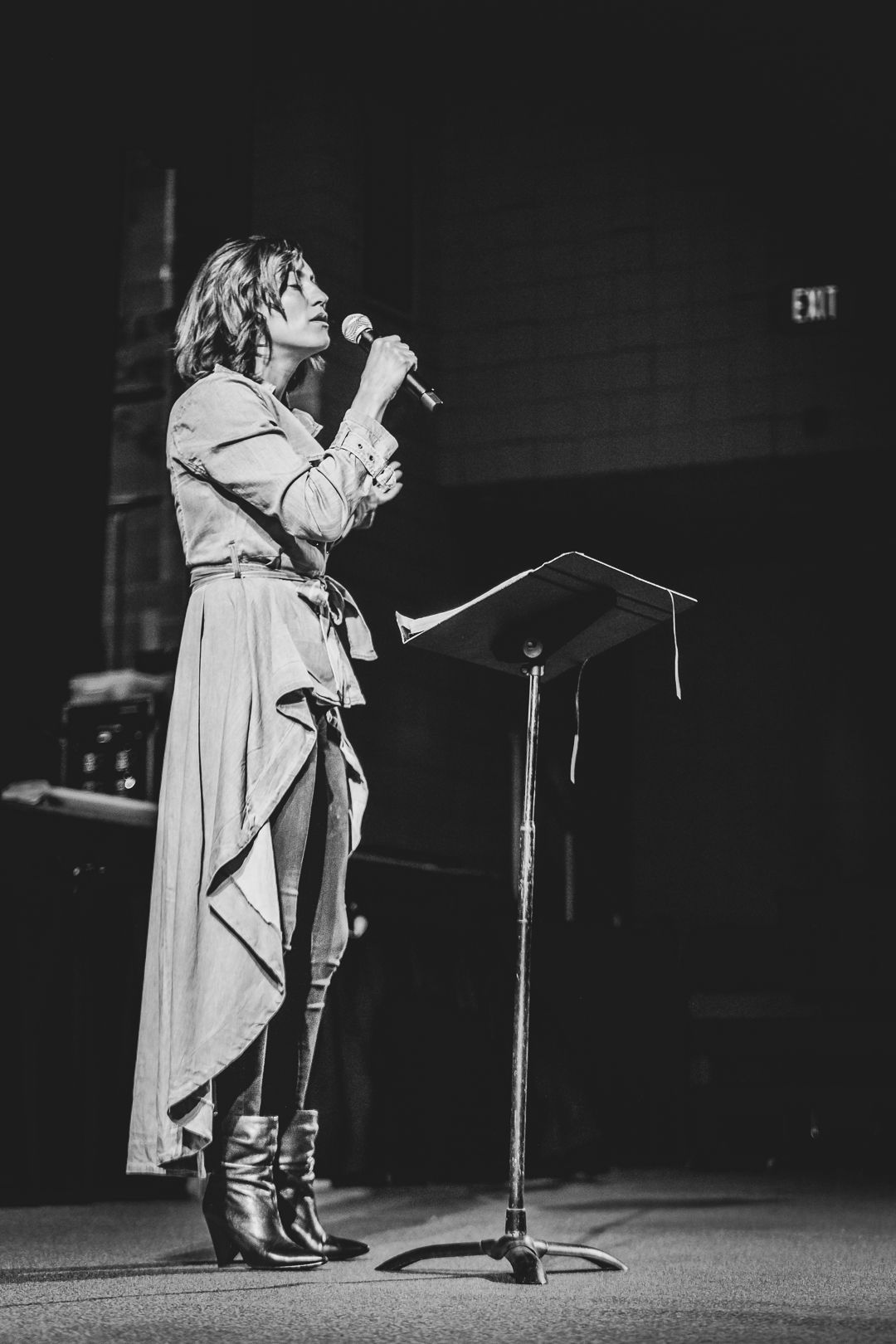 Female pastor standing in front of a church and speaking on a microphone