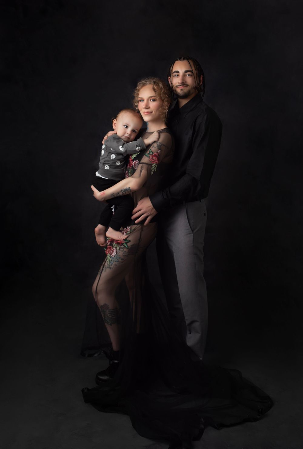 Artistic family portrait in dark tones with sheer floral dress.