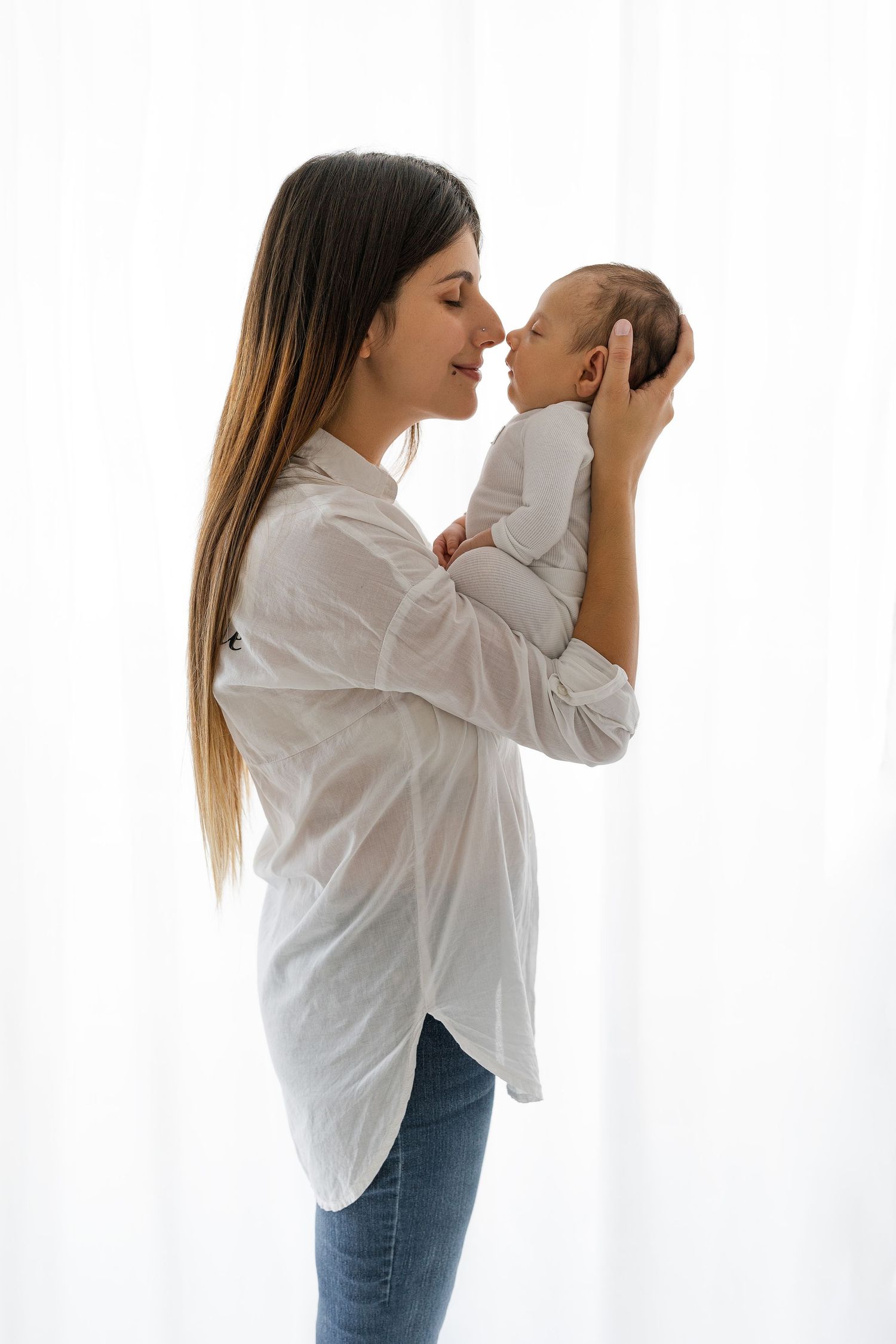 Tender parenting moment against bright window background.
