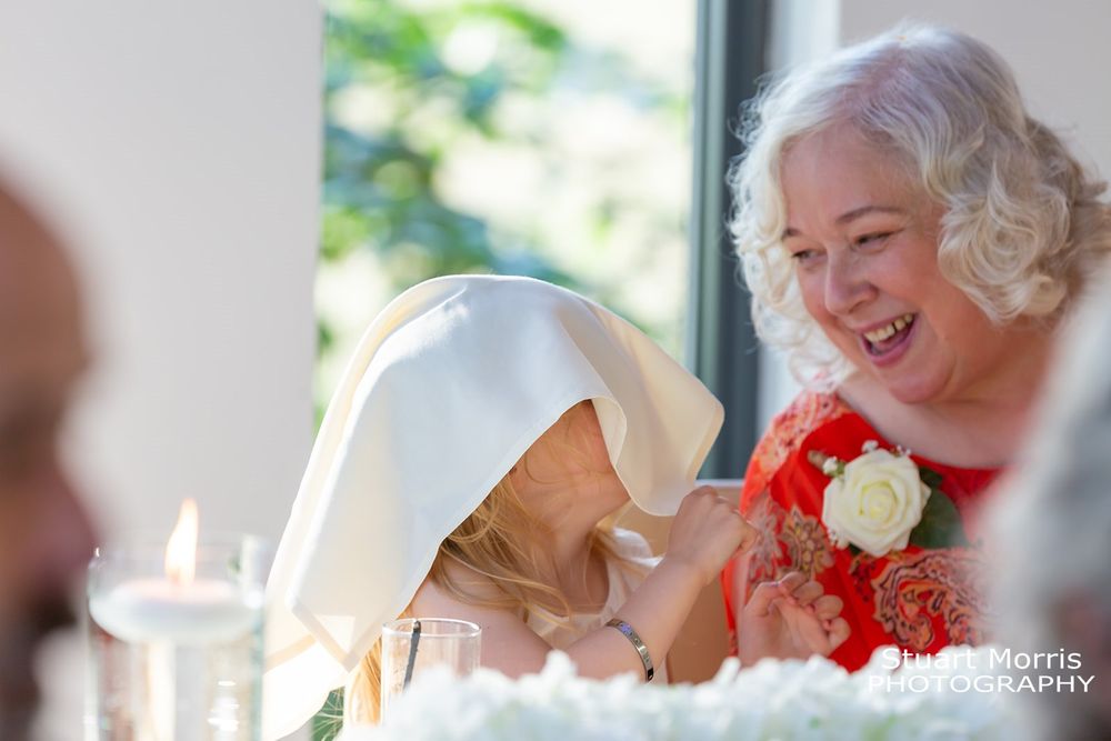Flowergirl puts a napkin over her head during the wedding breakfast at west tower wedding venue.
