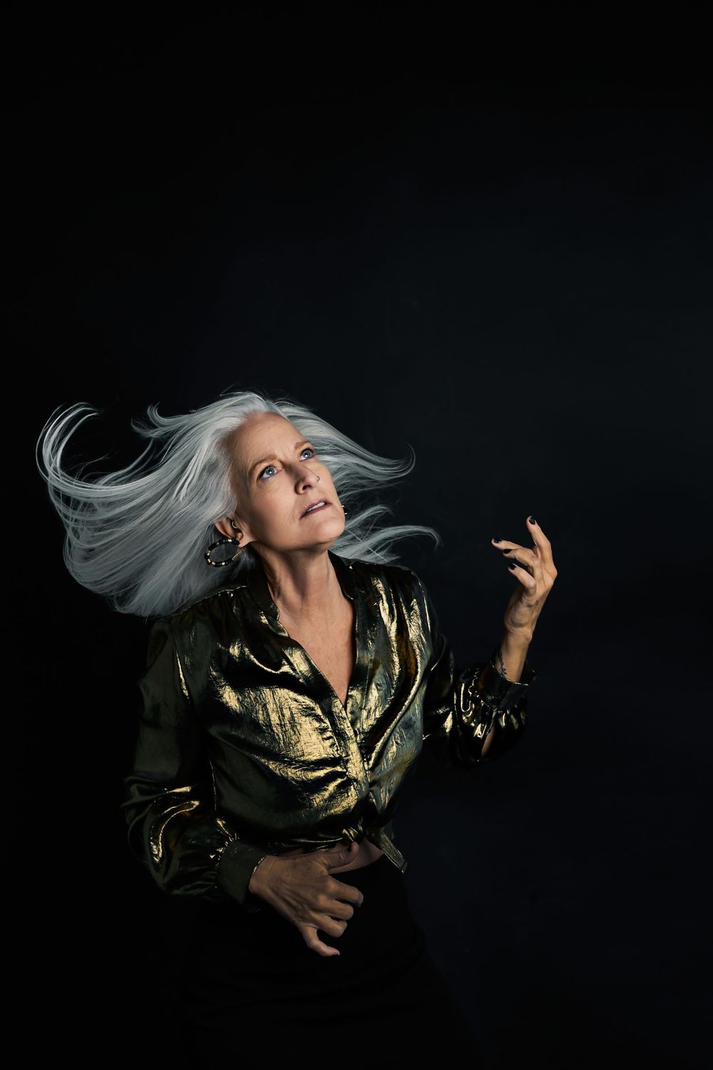 Expressive dance-like motion captured with flowing hair and metallic gold jacket.