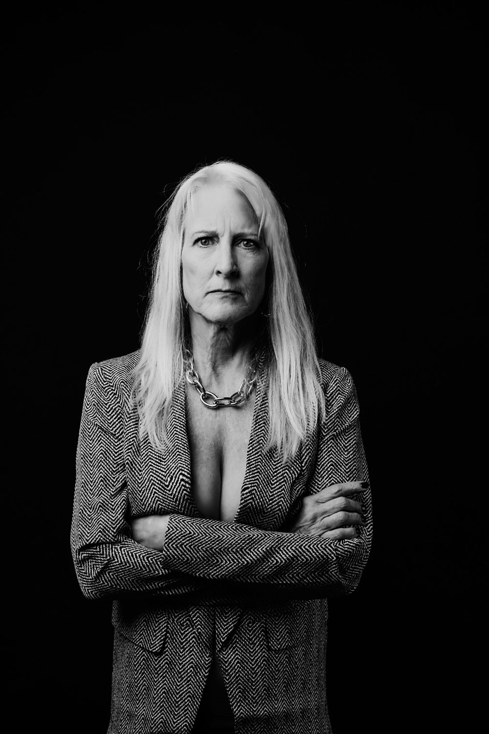 Professional black and white portrait series showing a person in a patterned blazer against dark background.