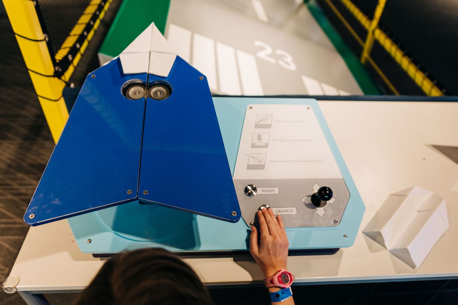 Girl's hand hitting launch on a paper airplane shooter at Monroe Science Center