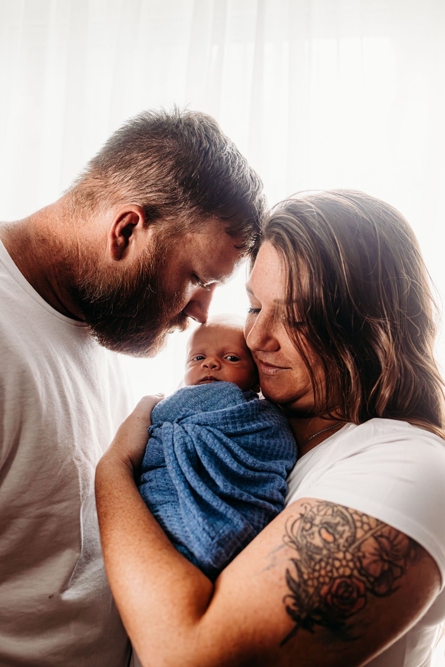 Intimate family portrait in soft window light against white backdrop.