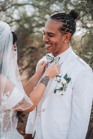 An intimate wedding moment showing a bride adjusting the groom's bowtie.