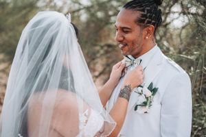 A sweet candid moment of wedding couple interaction in white attire.