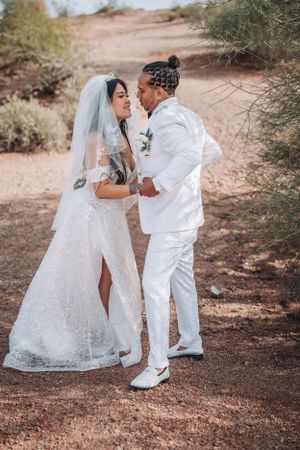 A romantic desert wedding portrait of a couple in elegant white attire.