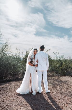 Intimate wedding moment captured in desert setting with couple in all-white attire.