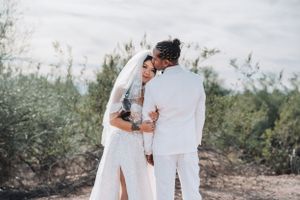 Romantic desert wedding portrait showing tender embrace against natural landscape.