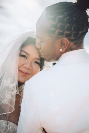 Close-up wedding photo showing tender moment between newlyweds with soft natural lighting.