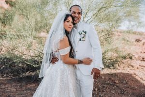 A joyful wedding embrace captured in the desert with the couple wearing elegant white wedding attire.
