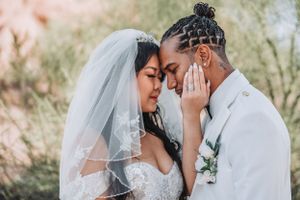 Romantic wedding portrait showing gentle embrace between newlyweds in white attire.
