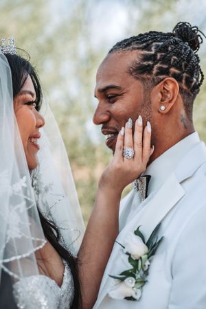 Candid wedding photo showing loving couple in white formal attire sharing tender moment.