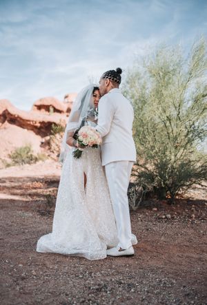 A wedding couple shares an intimate moment against a desert landscape backdrop.