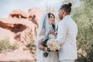 A tender wedding moment captured in front of dramatic red rock formations.