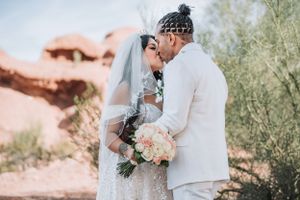 Newlyweds share a romantic moment among desert scenery with blush-colored florals.