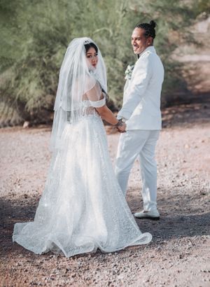 A wedding couple shares a moment together in the desert wearing elegant white attire.