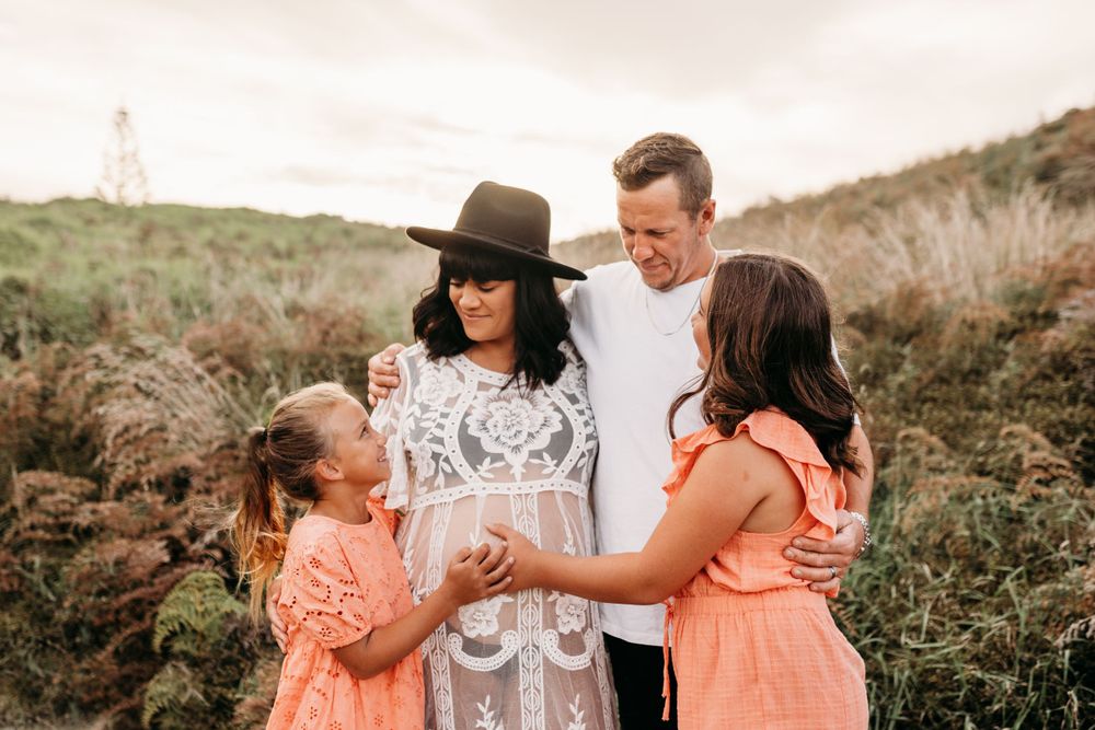 A family in coordinated outfits poses together on a hilltop at sunset.
