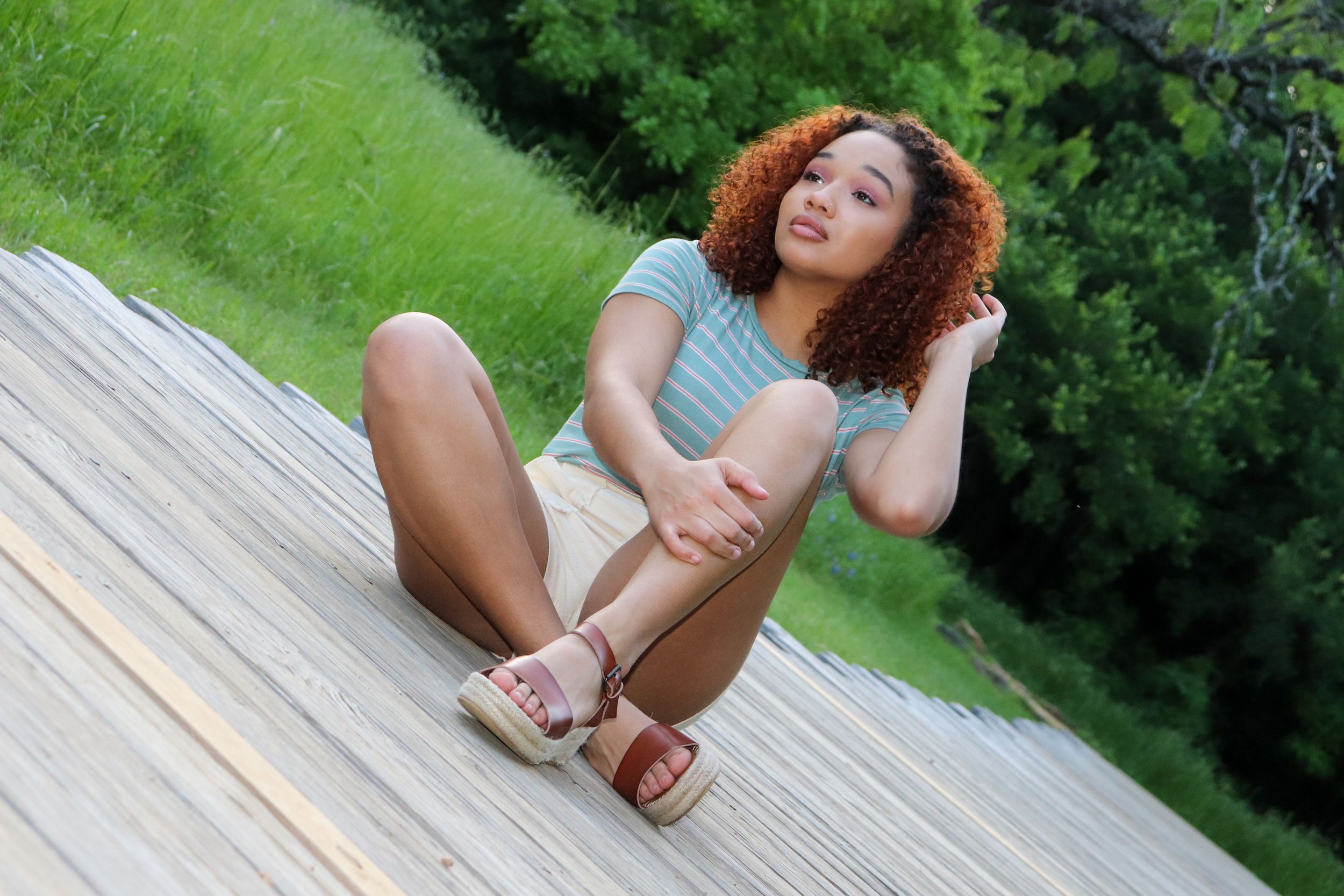 Person relaxing on wooden deck in casual summer attire.