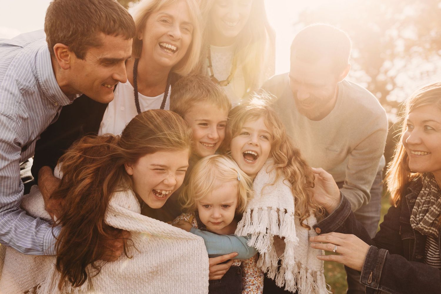 Group of people sharing joyful laughter together in warm sunlight.