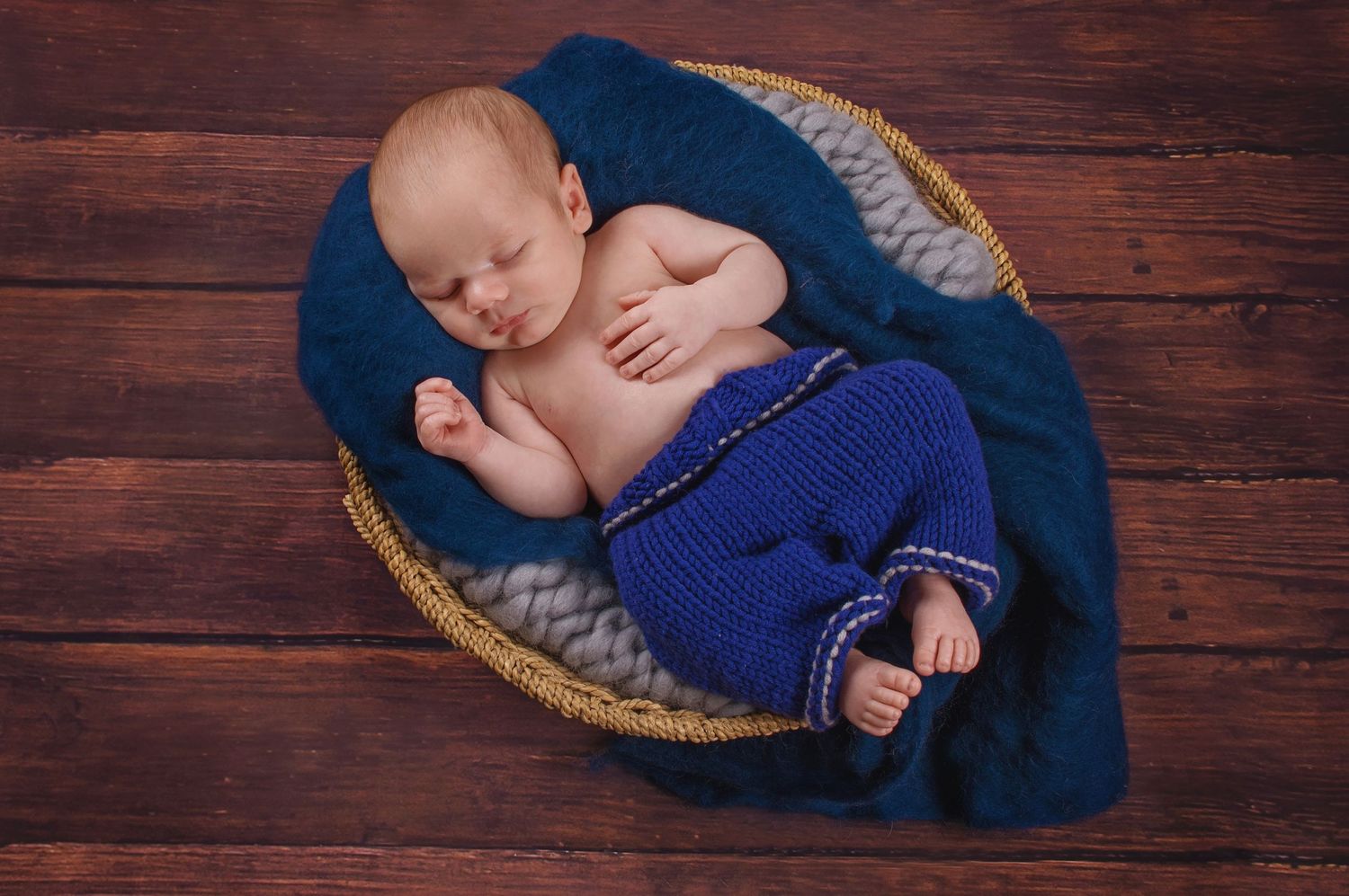 newborn photography of baby boy sleeping in basket with blue colours
